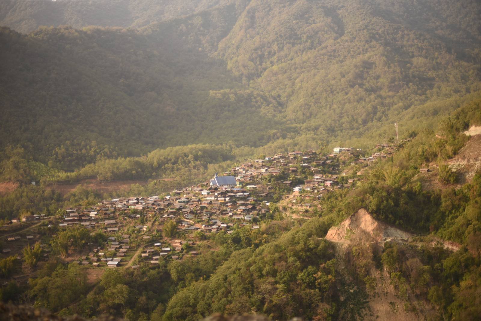 A hill village at golden hour surrounded by forested mountains